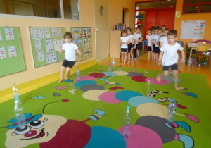 Dzieci biegają slalomem pomiędzy plastikowymi butelkami.